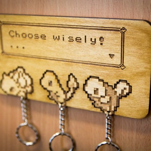 May include: Wooden key holder with a pixelated image of three Pokemon characters and the text "Choose wisely!"
