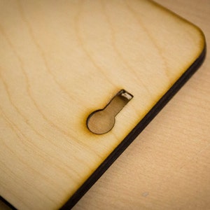 May include: A close-up of a light brown wooden sign with a keyhole cut out. The sign has a dark brown border.