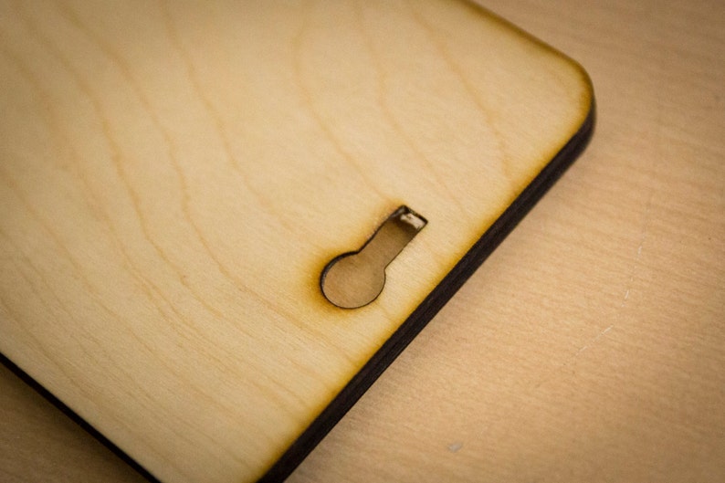May include: A close-up of a light brown wooden sign with a keyhole cut out. The sign has a dark brown border.