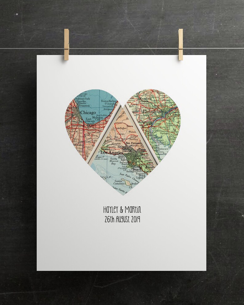 May include: A white print featuring a heart-shaped design composed of vintage map sections. The maps depict Chicago, Los Angeles, and Philadelphia. The names "Hayley & Martin" and the date "26th August 2019" are printed below the heart.