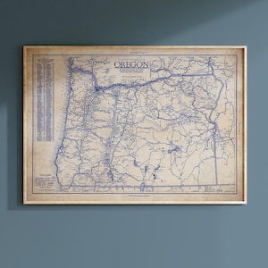 May include: A vintage map of Oregon, featuring a detailed road network in blue ink on a tan background. The map is framed in a light wood frame and includes the text "Oregon" at the top.