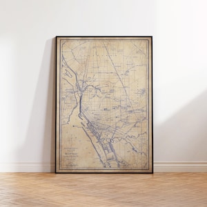 Peut inclure: Carte vintage encadrée de Buffalo et ses environs, imprimée à l'encre bleue sur papier vieilli. La carte présente des rues détaillées et des cours d'eau. Le cadre noir est posé contre un mur blanc.