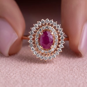 May include: A rose gold ring with a large oval ruby surrounded by a halo of smaller diamonds.