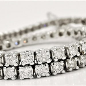 May include: A silver tennis bracelet with a double row of round, clear diamonds.