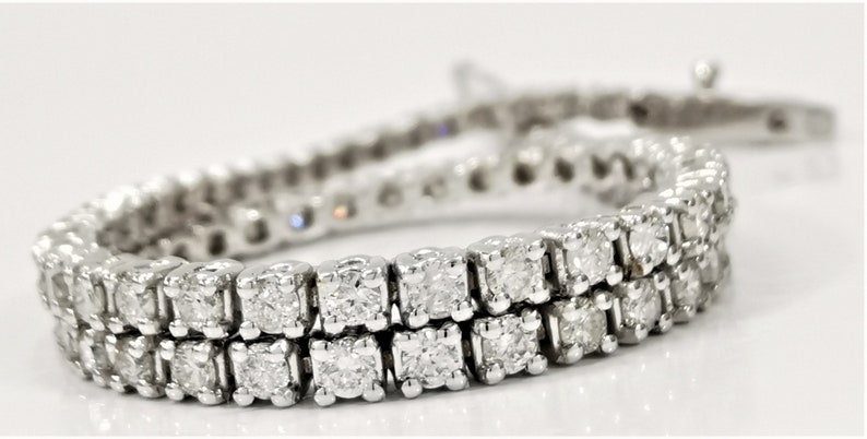 May include: A silver tennis bracelet with a double row of round, clear diamonds.