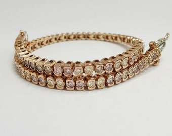 May include: A rose gold tennis bracelet with a double row of round, clear and pink diamonds.