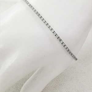 May include: A delicate silver tennis bracelet with small, sparkling diamonds set in a continuous line.