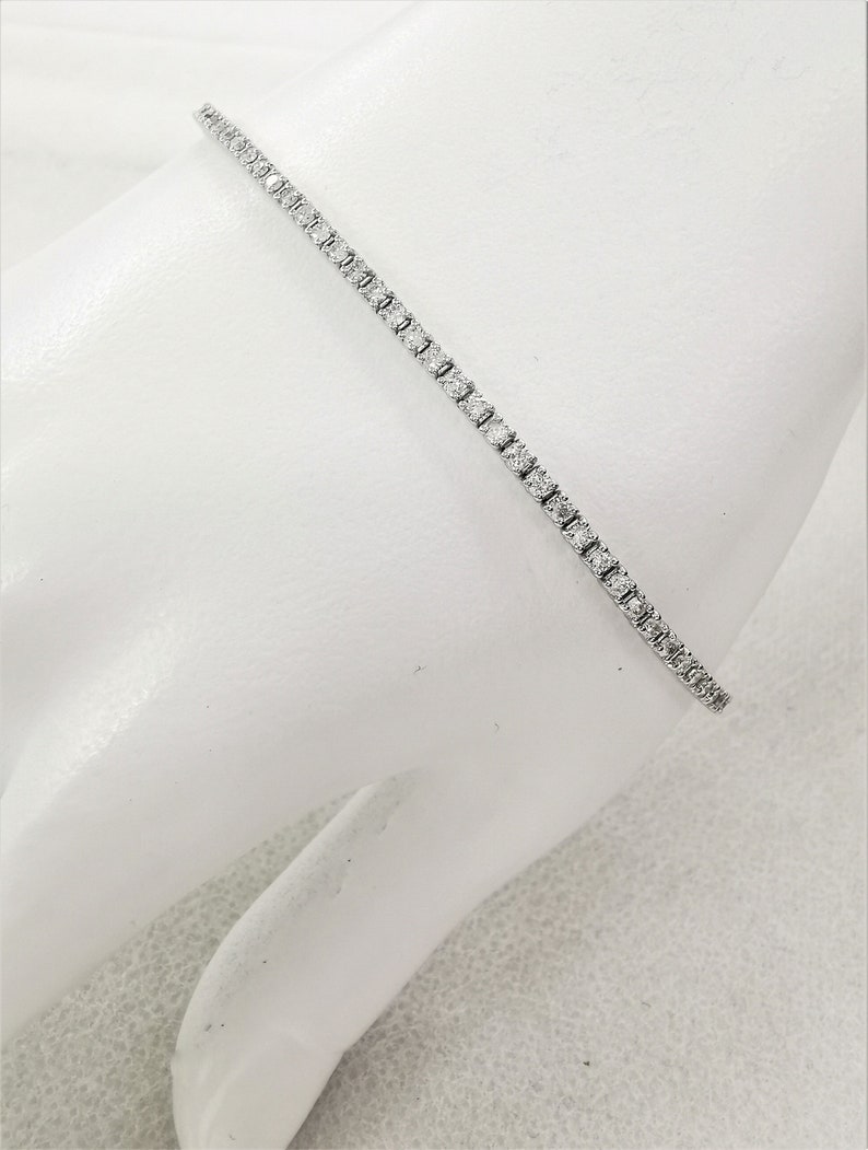 May include: A delicate silver tennis bracelet with small, sparkling diamonds set in a continuous line.