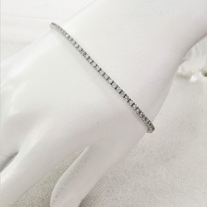 May include: A delicate silver tennis bracelet with a row of small, sparkling diamonds.