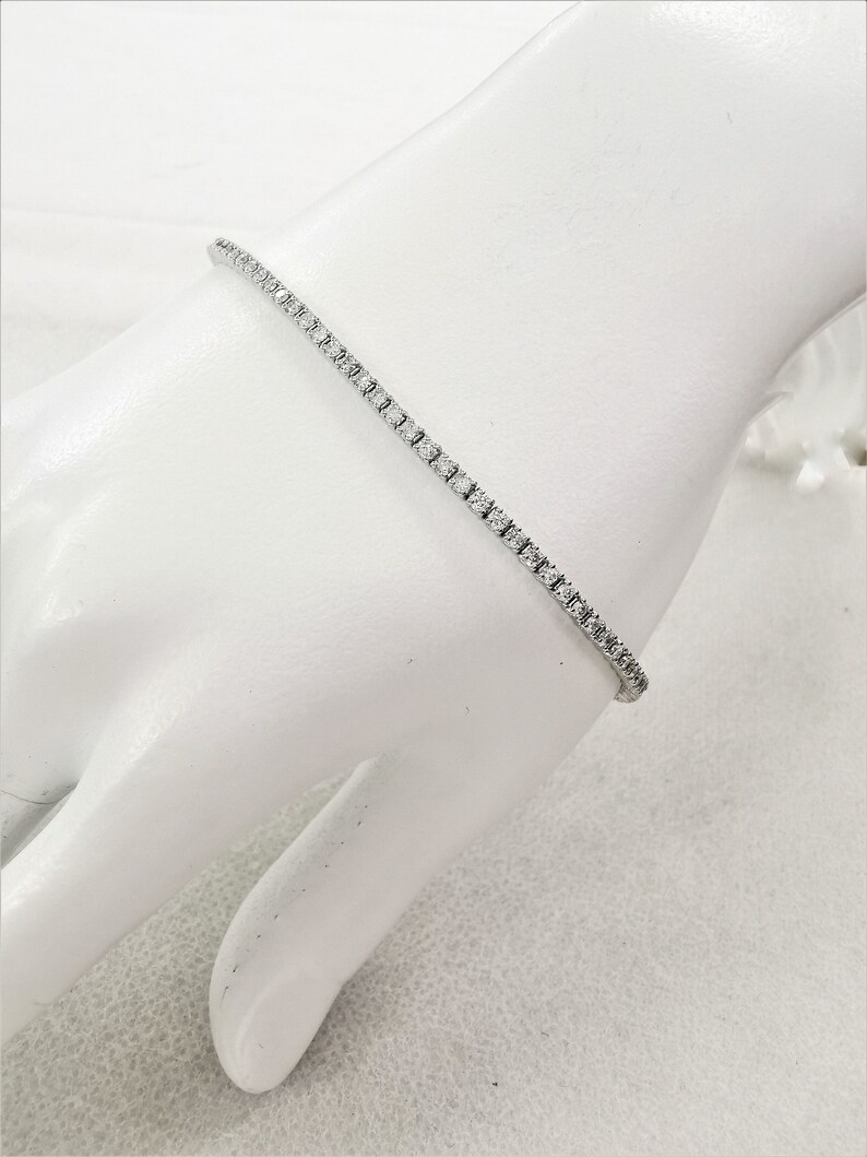 May include: A delicate silver tennis bracelet with a row of small, sparkling diamonds.