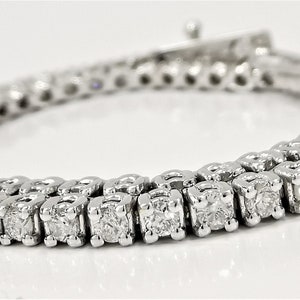May include: A white gold tennis bracelet with a row of round brilliant diamonds.