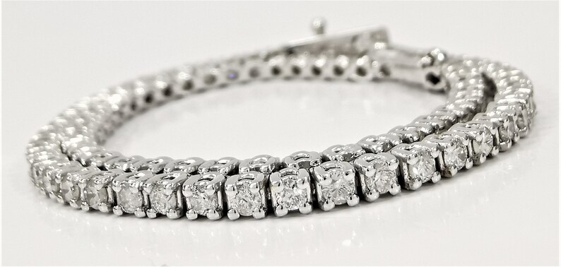 May include: A white gold tennis bracelet with a row of round brilliant diamonds.