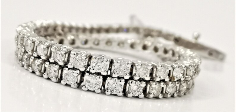 May include: A double row diamond tennis bracelet with a white gold setting. The bracelet is made of small, square-shaped diamonds.
