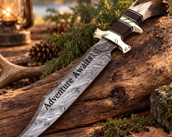 May include: A fixed-blade knife with a Damascus steel blade featuring the text Adventure Awaits. The handle is crafted from dark wood and antler, accented with a polished brass guard and pommel, showcasing a distinct layered metal pattern.