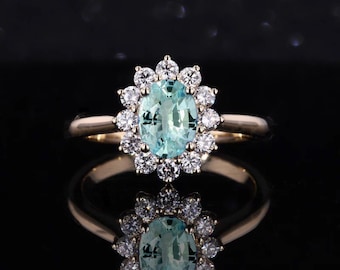 May include: A gold ring with a large oval aquamarine gemstone surrounded by a halo of smaller diamonds.