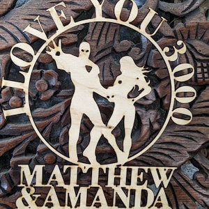 May include: Wooden cake topper with a circle design featuring the words "I Love You 3000" and two figures dancing. Below the circle is the text "Matthew & Amanda".