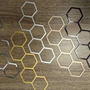 May include: Three sets of hexagonal metal wall decor in silver, gold, and black. Each set is arranged in a honeycomb pattern.
