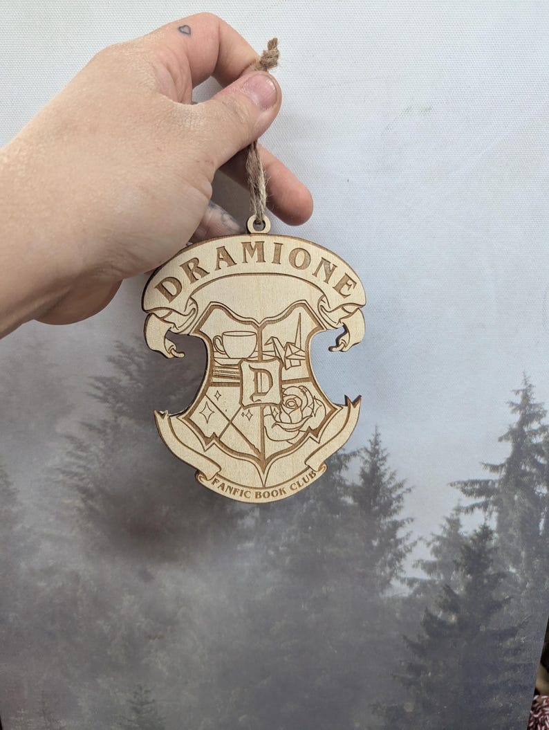 May include: Wooden ornament with a crest featuring a cup, a rose, and the text "Dramione Fanfic Book Club".