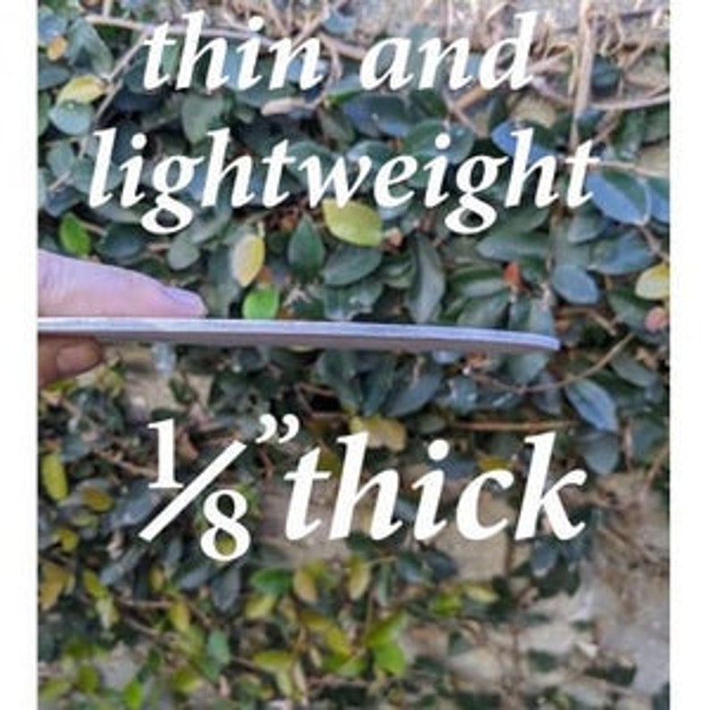 May include: Close-up of a thin, silver metal sheet. The sheet is 1/8 inch thick and is being held by a hand.
