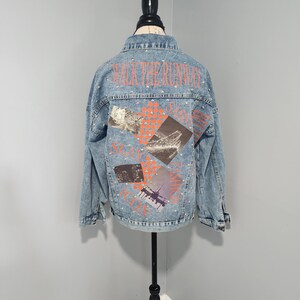 May include: A light blue denim jacket with rhinestones and a graphic print on the back that says "Walk the Runway" with images of a Ferris wheel, a cityscape, and an airplane.