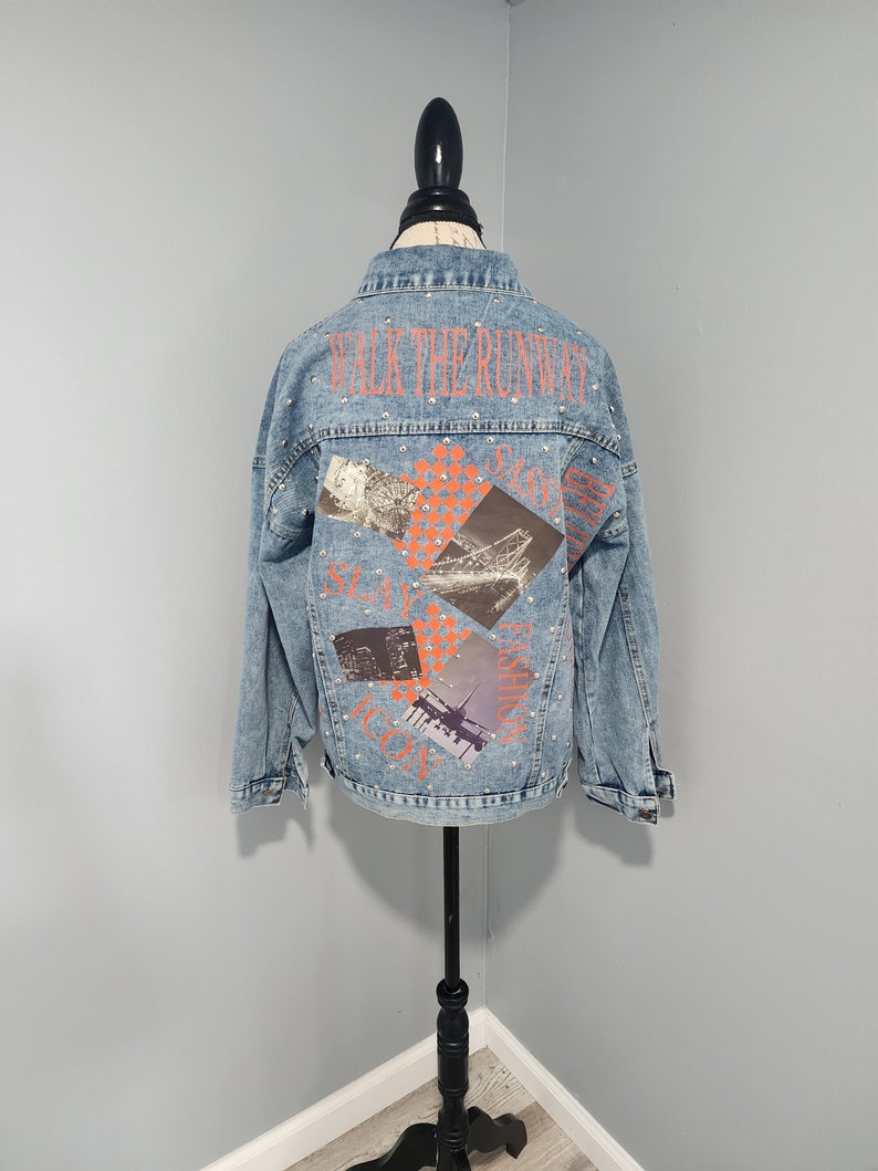 May include: A light blue denim jacket with rhinestones and a graphic print on the back that says "Walk the Runway" with images of a Ferris wheel, a cityscape, and an airplane.
