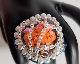 Puede incluir: Un anillo con un gran corazón de purpurina naranja rodeado de una cadena plateada y perlas blancas.