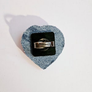 K&ouml;nnte beinhalten: Ein herzf&ouml;rmiger Ring aus Jeans mit einem silbernen Band und einer schwarzen R&uuml;ckseite.