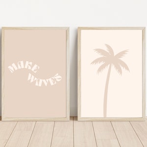 May include: Two framed prints with a beige background. The print on the left has the text "MAKE WAVES" in white. The print on the right has a silhouette of a palm tree in beige.