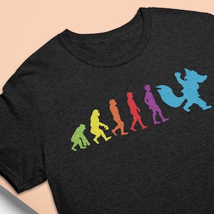 May include: Dark grey t-shirt with a rainbow-coloured evolution graphic. The graphic shows a progression from ape to a furry creature. The t-shirt has a crew neck and short sleeves. The design is printed on the front.
