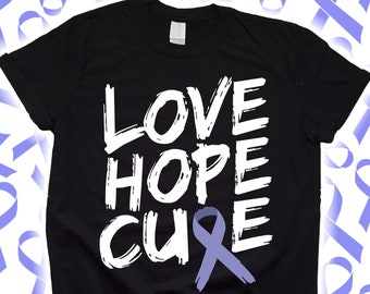 Puede incluir: Camiseta negra con las palabras "LOVE HOPE CURE" en blanco y un lazo morado claro. La camiseta tiene cuello redondo y mangas cortas. El fondo presenta lazos morados claros.