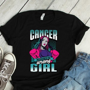 Puede incluir: Camiseta negra con un gráfico de una mujer con guantes de boxeo y el texto "Cancer. Messed with the wrong girl."