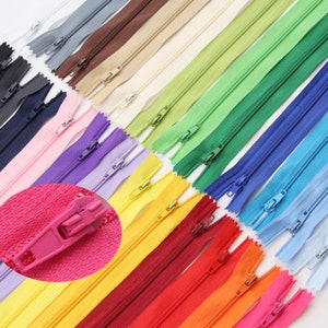 Può includere: Assortimento di nastri per cerniere colorati in varie tonalità, tra cui rosa, giallo, blu, verde e rosso. Le cerniere sono disposte in file, mostrando i diversi colori e stili.