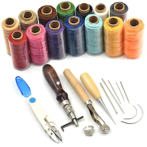 Pode incluir: Um conjunto de ferramentas e suprimentos para trabalhar o couro, incluindo 12 carretéis de linha encerada em várias cores, um furador para costura, um ranhurador para costura, um dedal, um abridor de costuras e quatro agulhas.