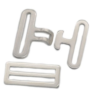 Puede incluir: Juego de hebillas de metal plateado para proyectos de costura. El juego incluye dos piezas de hebilla y un deslizador. Las piezas de hebilla tienen forma de T con un agujero en la parte superior. El deslizador es rectangular con dos ranuras paralelas.