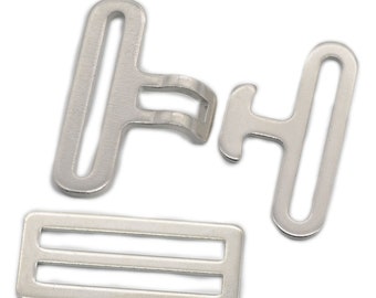 Puede incluir: Juego de hebillas de metal plateado para proyectos de costura. El juego incluye dos piezas de hebilla y un deslizador. Las piezas de hebilla tienen forma de T con un agujero en la parte superior. El deslizador es rectangular con dos ranuras paralelas.
