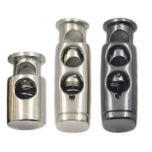 May include: Three metal cord stoppers in different sizes. The stoppers are silver and black and have a spring mechanism.