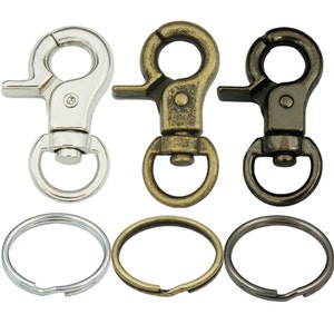 May include: Three sets of silver, brass, and black metal keychains with a swivel clasp and a round ring. Each keychain has a different finish.