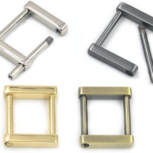 Könnte beinhalten: Vier Metall-Gürtelschließen in verschiedenen Ausführungen: Silber, Schwarz, Gold und Messing. Die Schließen sind rechteckig mit einer quadratischen Öffnung in der Mitte.