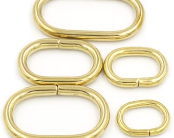 May include: Five brass oval rings of different sizes. The rings are smooth and shiny.