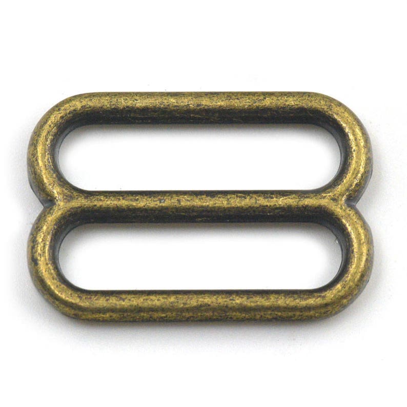 May include: Antique gold metal slider buckle with two loops. The buckle is designed for use with straps or belts.