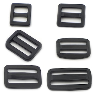 May include: Six black plastic slider buckles of various sizes. The buckles have two parallel slots and are commonly used for straps, bags, and other DIY projects.