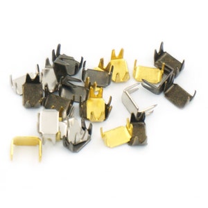 Könnte beinhalten: Eine Sammlung von Metall-Reißverschluss-Zierbändern in Gold, Silber und Schwarz. Die Reißverschluss-Zierbänder sind in verschiedenen Formen und Größen und einige haben ein dekoratives Design.