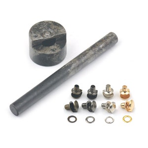 May include: A set of metal eyelets and a tool for installing them. The tool includes a hammer and a punch. The eyelets are available in different colors, including silver, gold, and black.