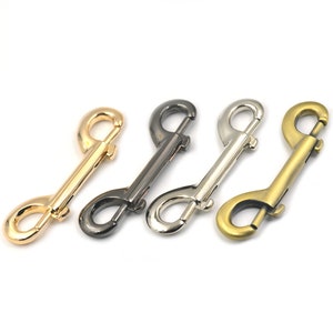 Peut inclure: Quatre mousquetons à bascule en métal dans différentes finitions : or, noir, argent et laiton antique. Les mousquetons sont tous de la même taille et de la même forme.