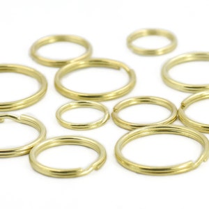 Puede incluir: Surtido de llaveros de metal dorado de varios tamaños. Los llaveros están dispuestos sobre una superficie blanca.