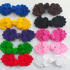 May include: Assortment of 10 pairs of colorful fabric Chinese knot buttons with pearl accents. The buttons are in various colors including blue, yellow, purple, green, red, pink, and white.