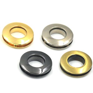 Peut inclure: Quatre œillets métalliques en différentes finitions : or, argent, noir et laiton. Les œillets sont ronds avec un trou au centre.