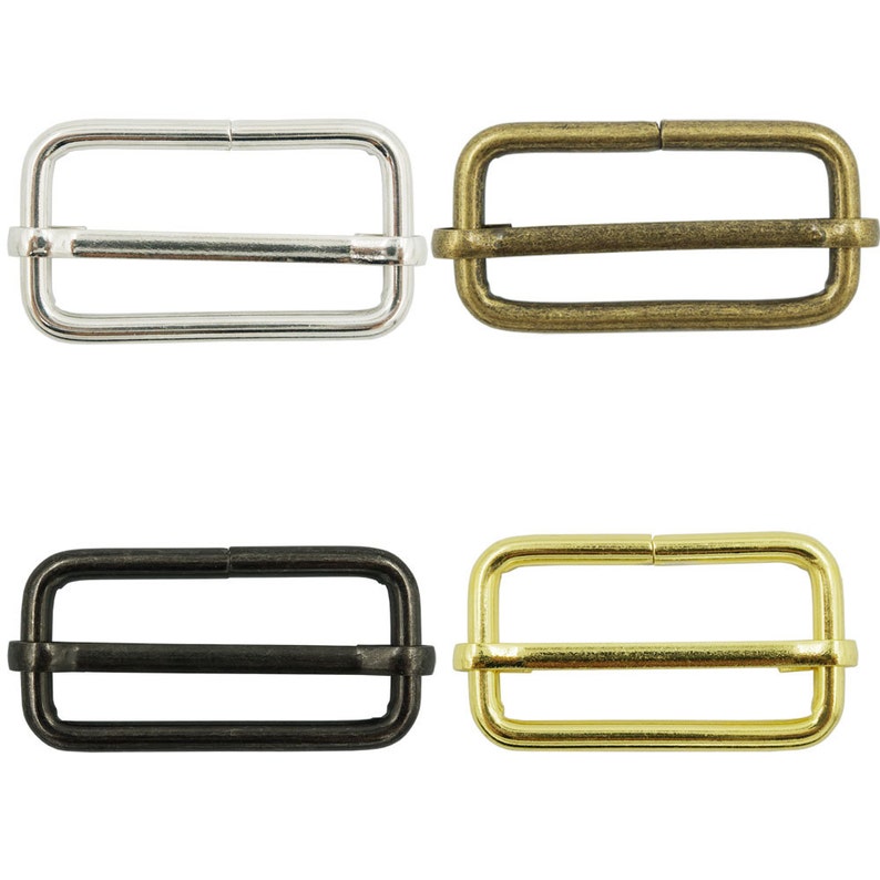 May include: Four metal slider buckles in different finishes: silver, antique brass, black, and gold. Each buckle is rectangular with a center bar.