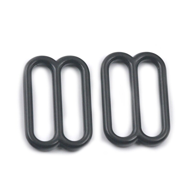 May include: Two black metal slider buckles. The buckles are designed to be used for adjusting the length of straps or belts.