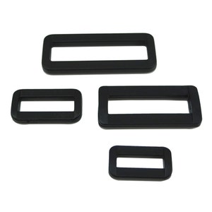 May include: Three black plastic slider buckles of different sizes. The buckles are rectangular with a rectangular opening in the centre.